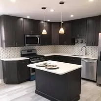 Remodeled kitchen with dark cabinets, a white island and pendant lights